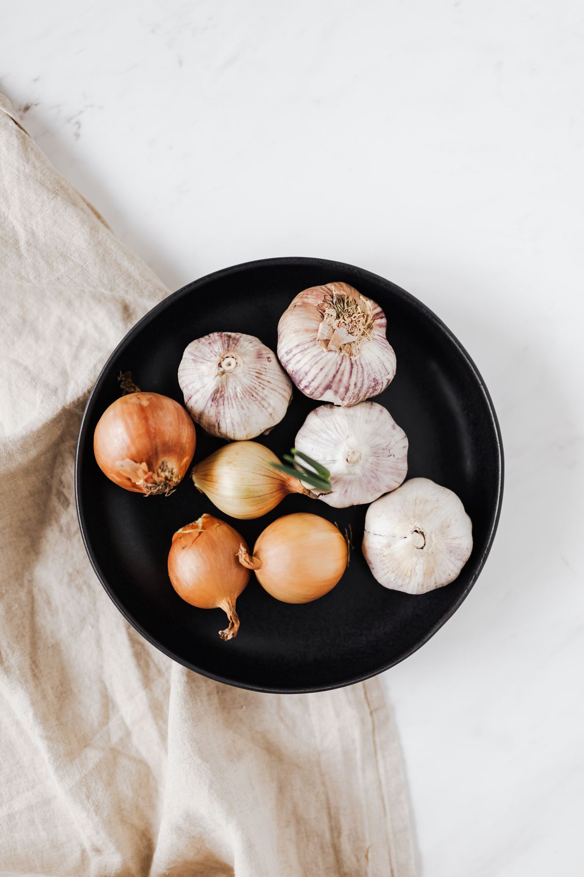 Cebollas y cabezas de ajo sobre un plato negro