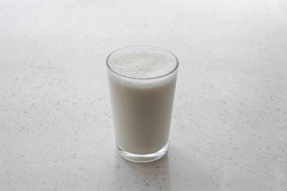 Vaso de leche sobre una superficie blanca